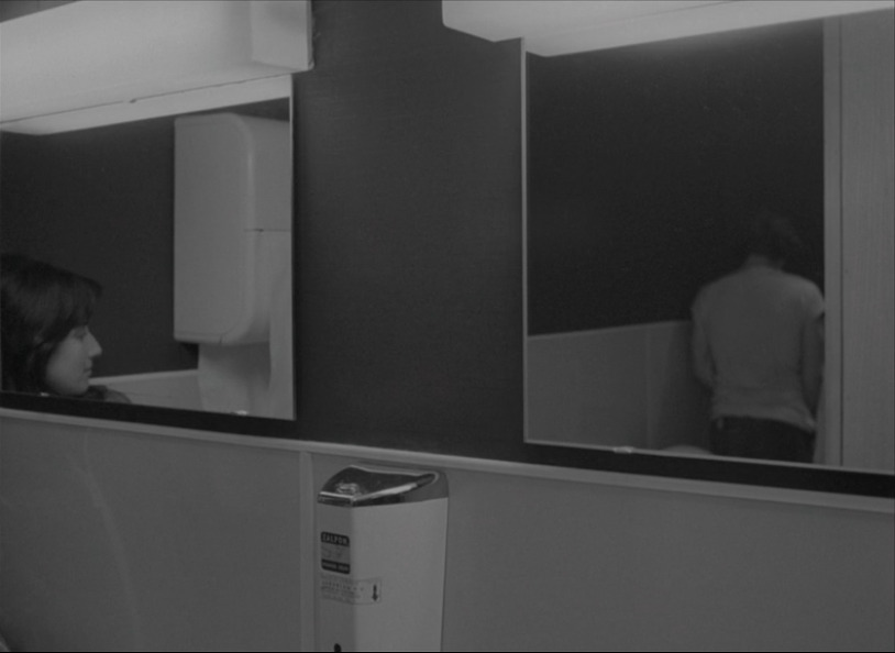A shot of two bathroom
      mirrors. Julie's reflection is in the left mirror, watching the
      driver, whose reflection appears in the right mirror, piss in a urinal